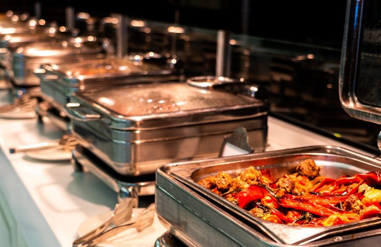 Buffet mit verschiedenen Gerichten in silbernen Warmhaltebehältern.