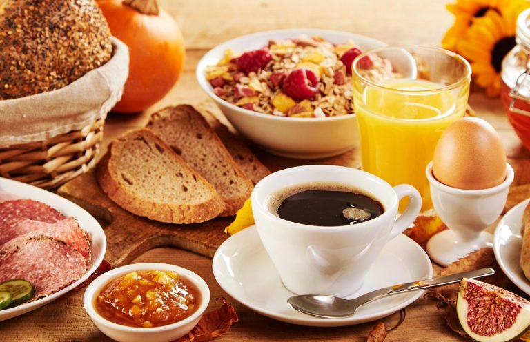 Ein reichhaltiges Frühstück mit Brot, Marmelade, Ei, Müsli, Kaffee und Orangensaft.